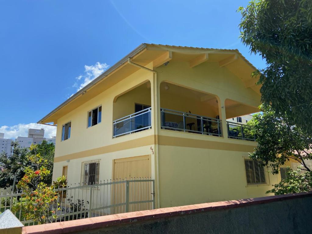 Una casa amarilla con balcón en la parte superior. en Casa da Vovó, en Itapema
