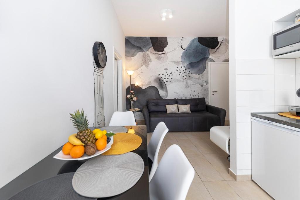 een keuken en een woonkamer met een tafel met fruit erop bij Apartments & Rooms Kolovare Beach in Zadar