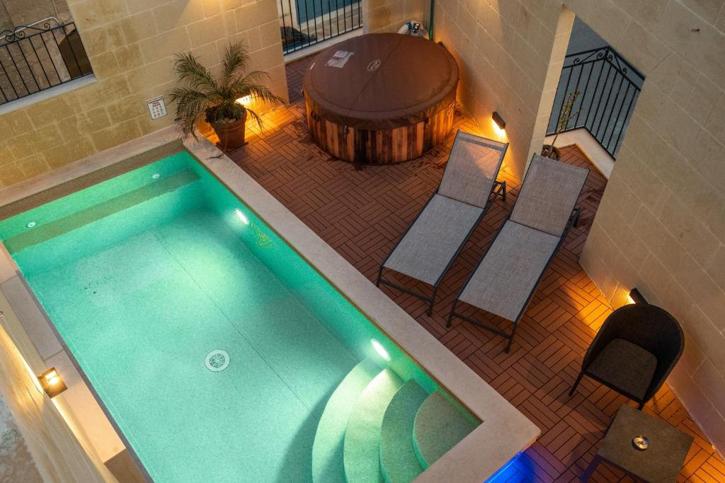an overhead view of a swimming pool with chairs and a barrel at Narcisa - Luxury 3BR Traditional House with Pool, Cinema & Hot Tub in Tal-Barmil
