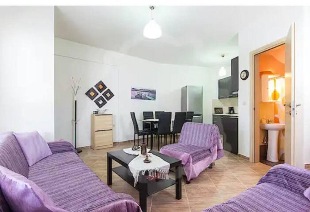 a living room with purple couches and a table at Villa Armonia in Skala Potamias