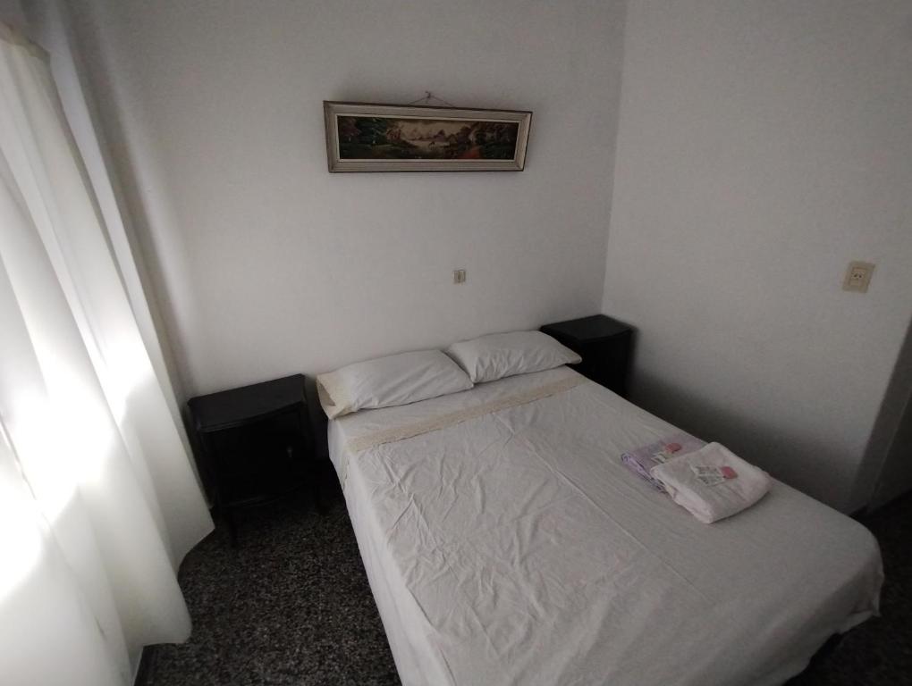 uma pequena cama num pequeno quarto com uma fotografia na parede em Hotel eden em Bahía Blanca
