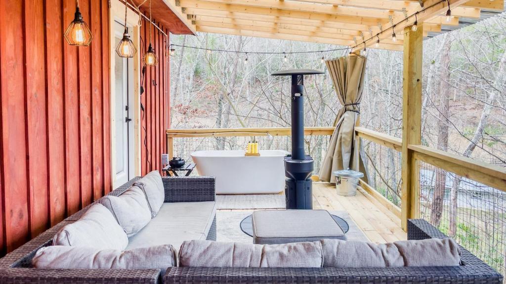 een bank op een afgeschermde veranda met een bad bij Romantic spot! Huge deck with outdoor soaking tub in Cosby