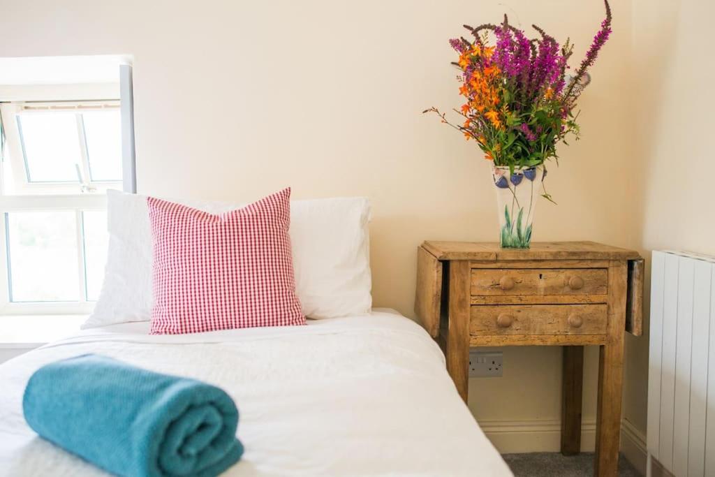 a bedroom with a bed with a vase of flowers on a table at Carleys Cottage in Fanore