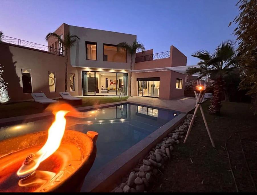 a house with a swimming pool with a fire in a tub at Villa aquaparc piscine chauffée sans vis à vis in Marrakech