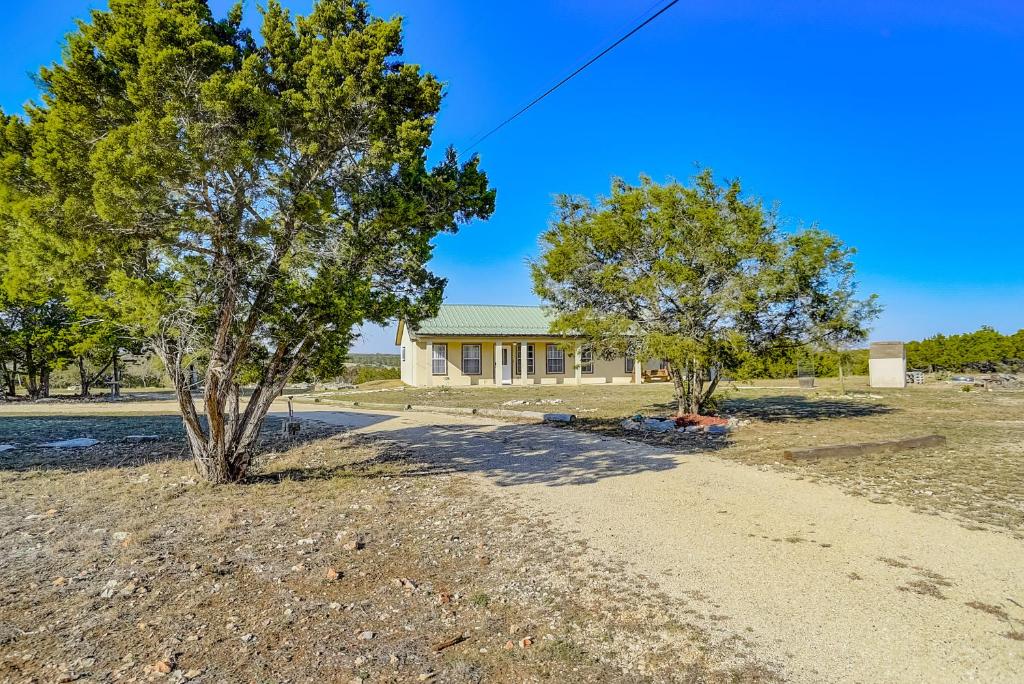 ein Haus mit zwei Bäumen und einem Feldweg in der Unterkunft Spicer Hill Hideaway in Kerrville