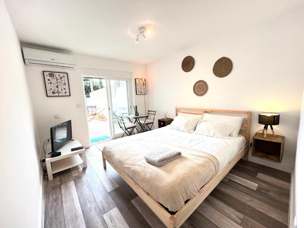 sypialnia z dużym białym łóżkiem i telewizorem w obiekcie IN-Cascais Suite Deluxe com pátio privado w mieście Cascais