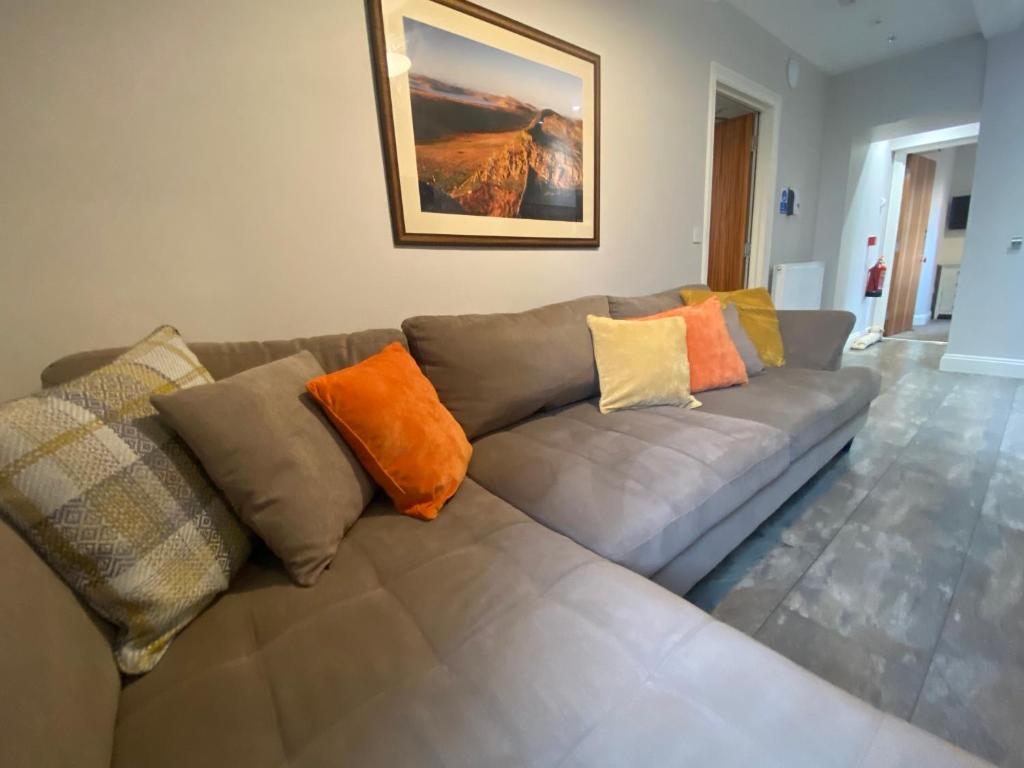 a living room with a gray couch with colorful pillows at Brampton Holiday Homes - Beckside Apartment in Brampton
