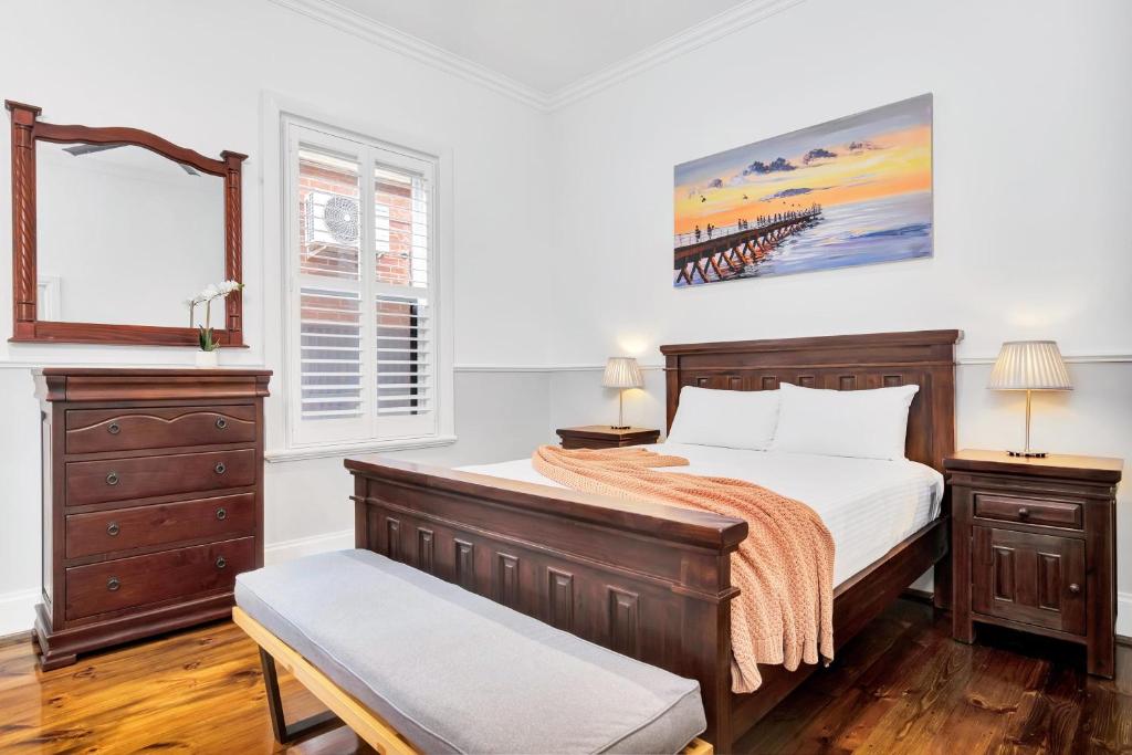 a bedroom with a bed and a dresser at Noir Cottage Glenelg North in Glenelg