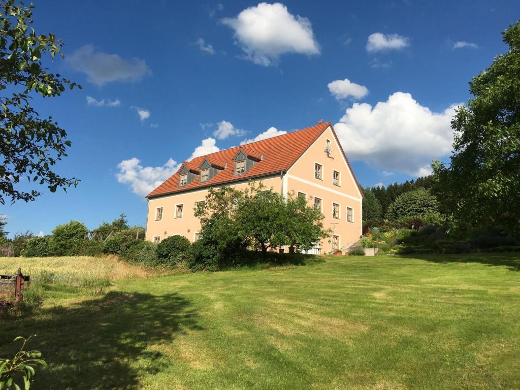 uma casa grande com um telhado vermelho num campo em Cozy group house with its own garden and wellness area em Schönsee