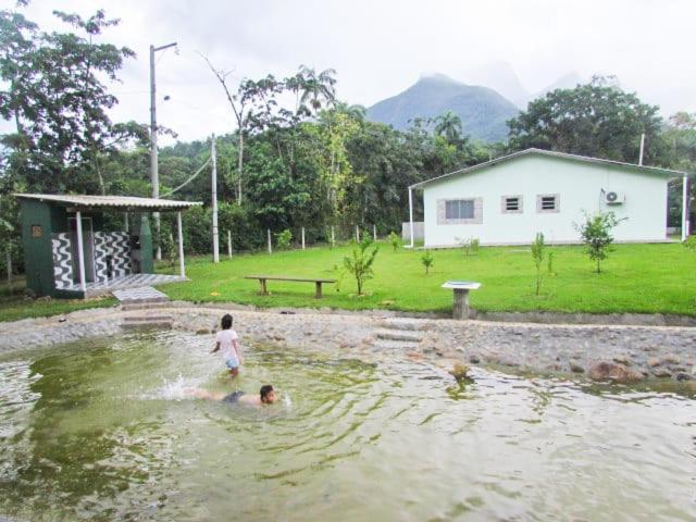 two children swimming in a pond in a yard at Chácara Rio Cachoeira in Antonina
