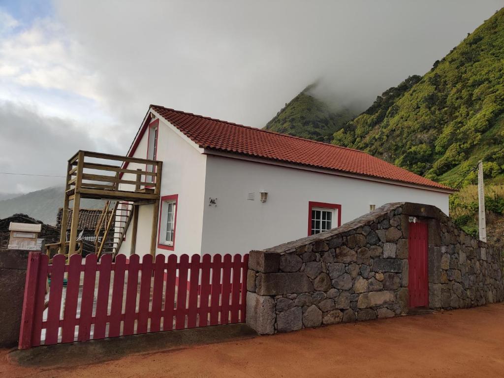 a white house with a red fence and a mountain at Casa da Eira in Calheta