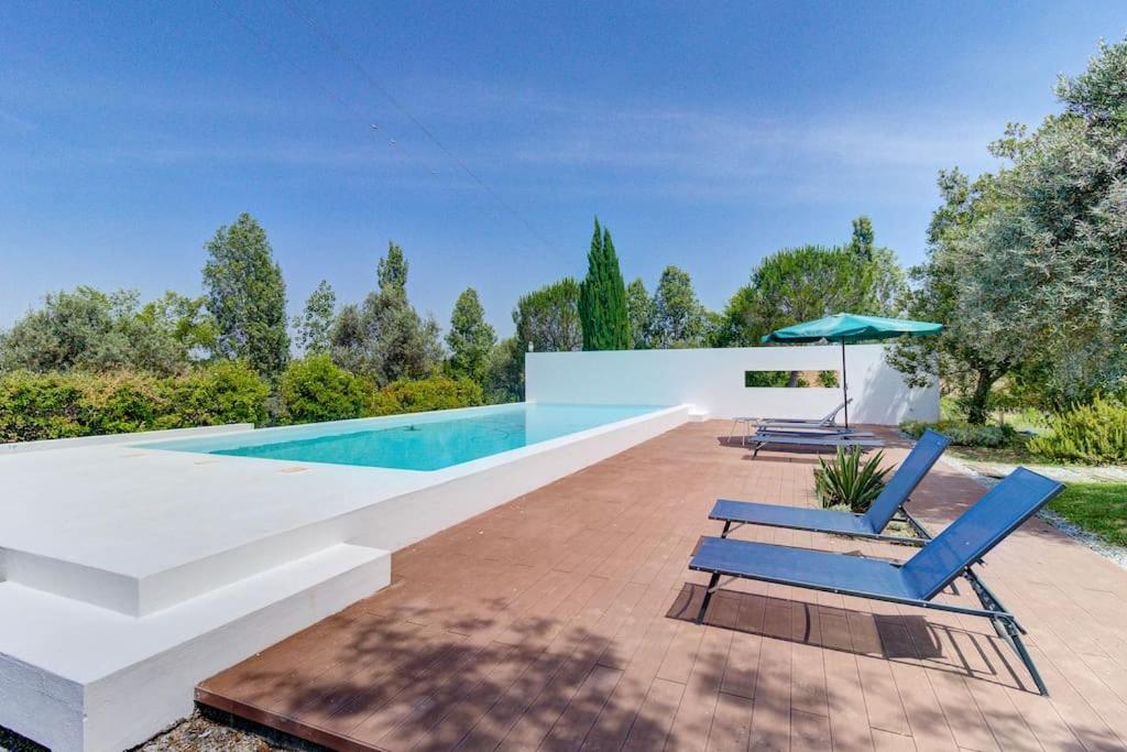 a swimming pool with two lounge chairs and an umbrella at Casa Koya- Luxury house in the countryside 