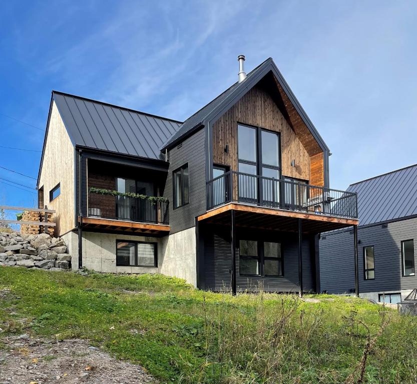a large house with a black roof at Chalet Snocamp in LʼAnse-Saint-Jean