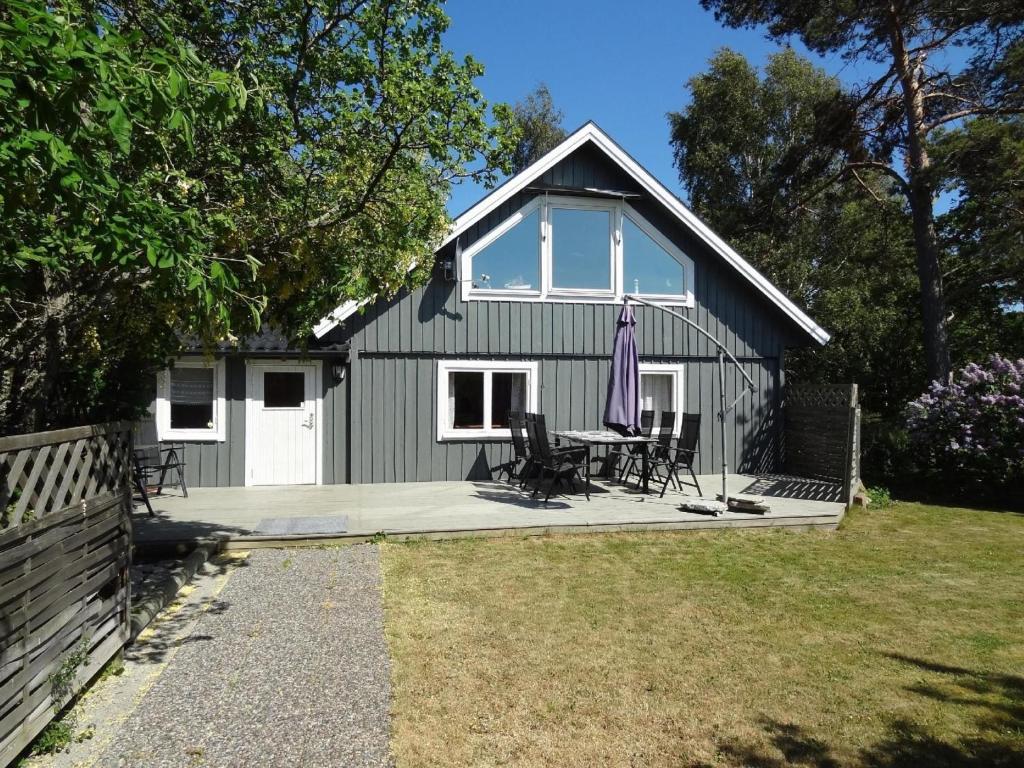 um barracão preto com uma mesa e cadeiras em frente em Gemütliches Ferienhaus mit Garten und Terrasse am Meer im Naturreservat em Södvik