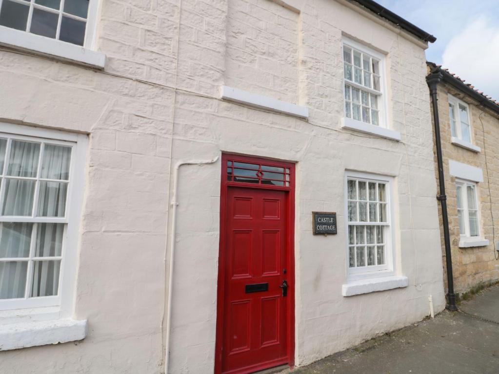 a red door on a white building with windows at 12 Castlegate in Pickering