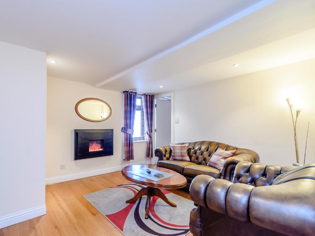 a living room with two leather couches and a table at Mermaid Cottage in Whitby