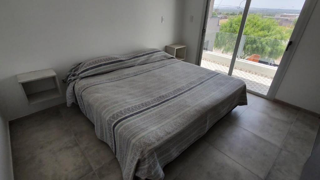 een bed in een slaapkamer met een groot raam bij Duplex en barrio privado in Mendoza