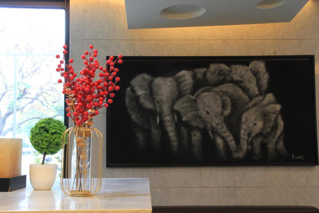 a vase with red flowers and a painting of elephants at The Galerie Hotel in Taichung