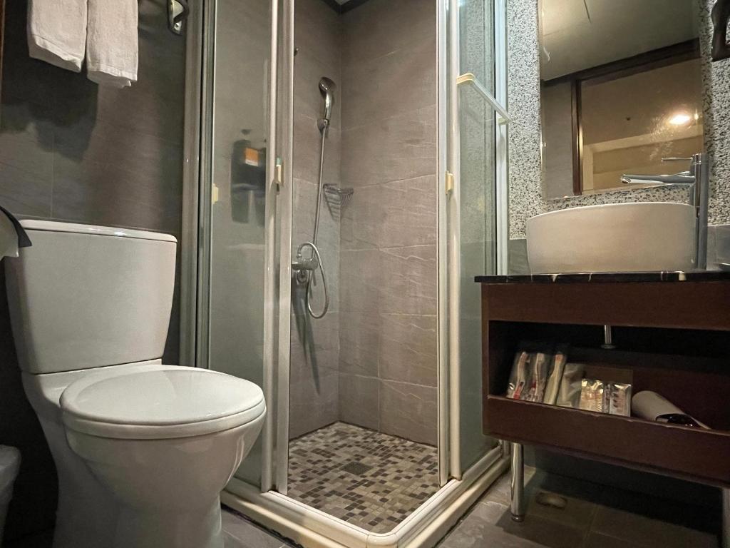 a bathroom with a shower and a toilet and a sink at The Galerie Hotel in Taichung
