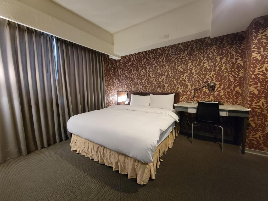 a hotel room with a large bed and a desk at The Galerie Hotel in Taichung