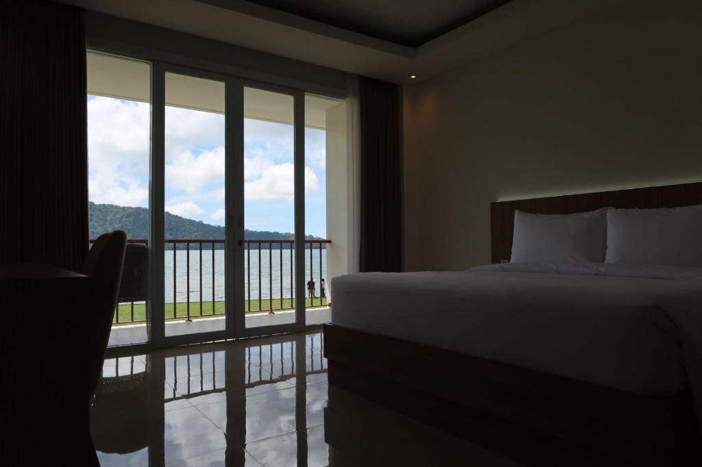 a bedroom with a bed and a view of a balcony at Rusa by The Lake in Baturiti