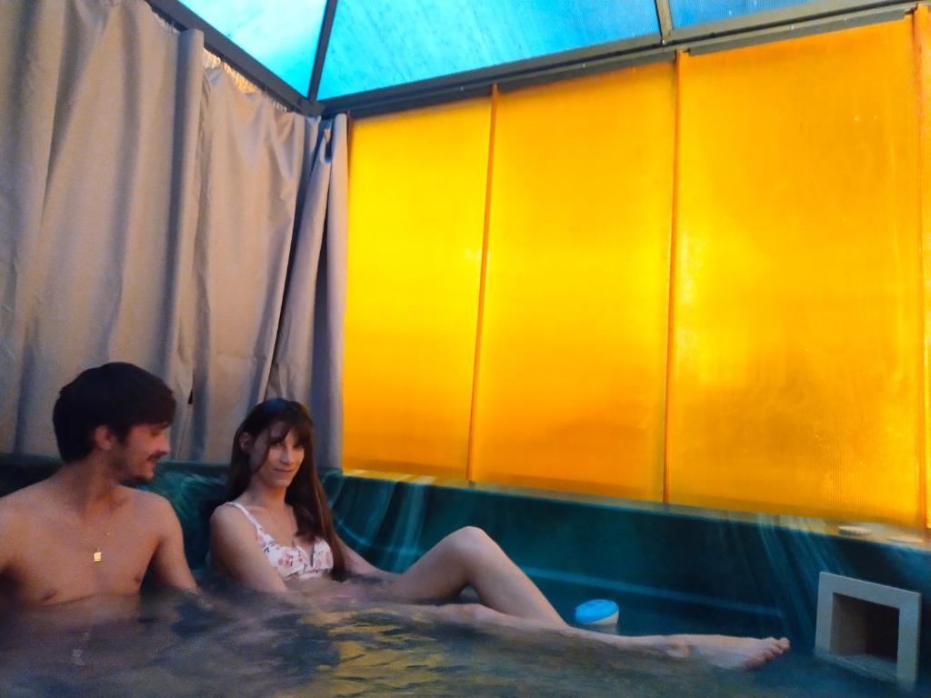 un homme et une femme assis dans un bain à remous dans l'établissement Spa Nimeslodge, à Nîmes
