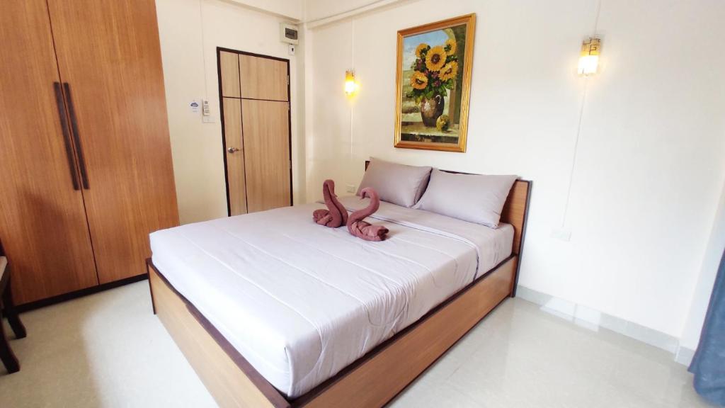a bed with a pink animal laying on top of it at 66 Apartment in Ban Khlong Nong Yai