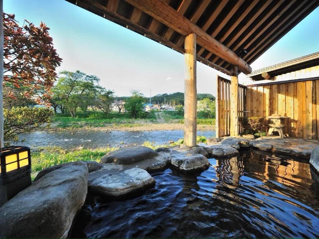 a pond with rocks in front of a house at Yunohara in Mogami