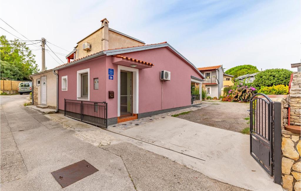 une maison rose dans une rue avec un portail dans l'établissement Lovely Apartment In Premantura With Wifi, à Premantura