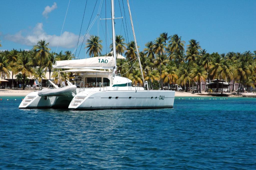 una barca bianca seduta in acqua accanto a una spiaggia di Catamaran TAO a Sainte-Anne