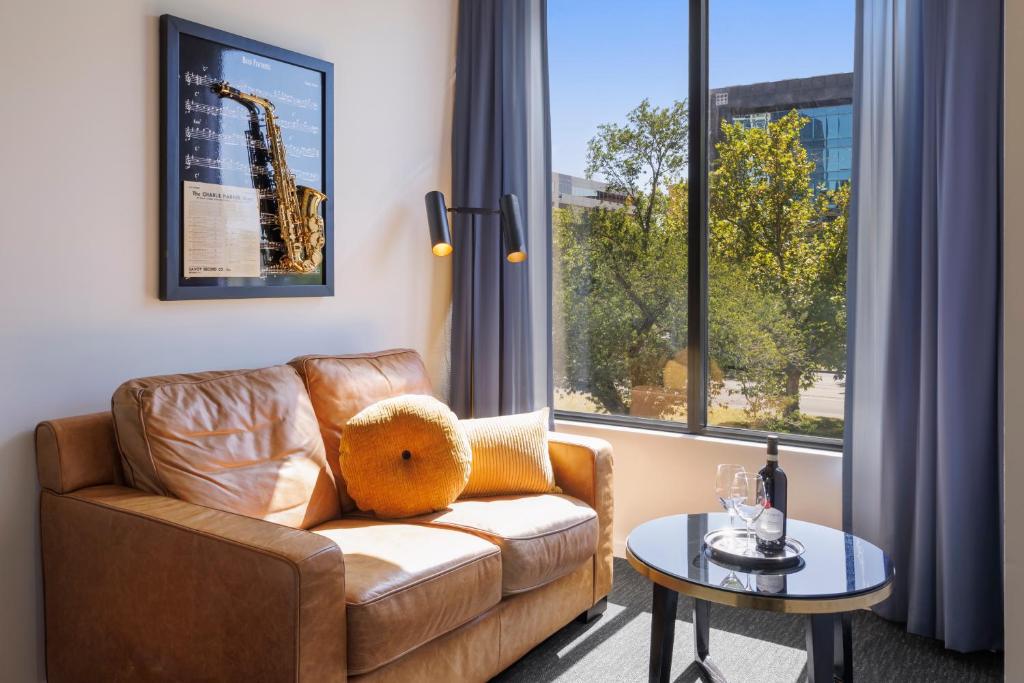a living room with a couch and a table and window at Mercure Melbourne St Kilda Road in Melbourne