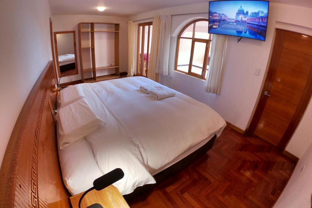 een slaapkamer met een groot bed en een tv aan de muur bij Akilpo Home in Huaraz