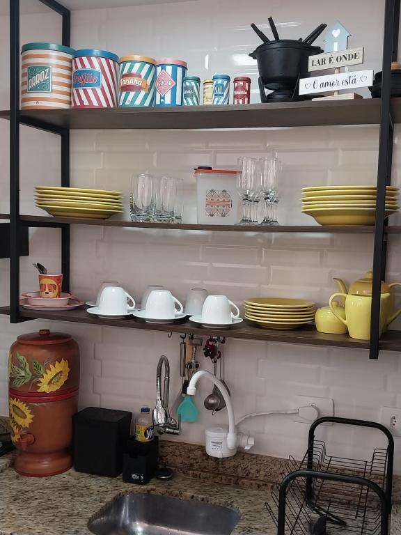 a kitchen counter with plates and dishes on shelves at Apartamento Conforto in Curitiba