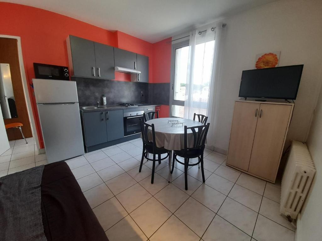 a kitchen with a table and a kitchen with red walls at T2 Centre-ville La Roche-Posay, proche Thermes, Wi-Fi, laverie - FR-1-541-79 in La Roche-Posay