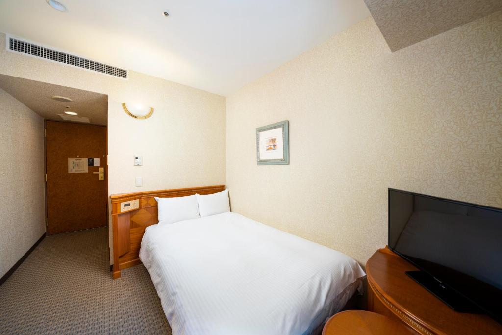 a hotel room with a bed and a flat screen tv at KOKO Hotel Nagoya Sakae in Nagoya