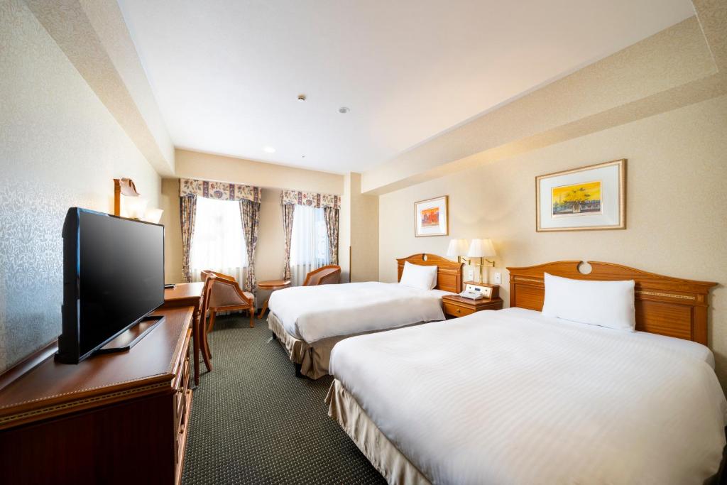 名古屋市にあるKOKO HOTEL Nagoya Sakaeのベッド2台、薄型テレビが備わるホテルルームです。