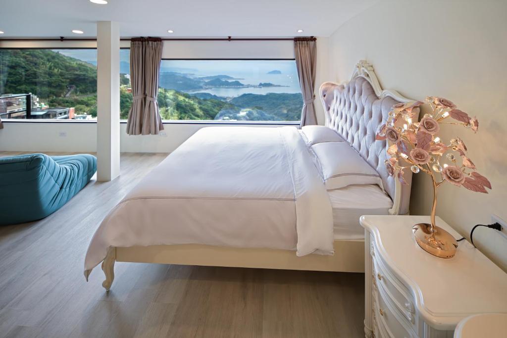 a bedroom with a large bed with a large window at Windsor's Sunlight Han-Guan in Jiufen
