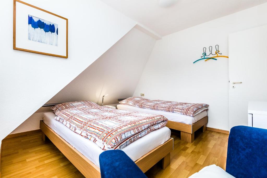 2 Betten in einem Zimmer mit blauen Stühlen in der Unterkunft Apartments Bensberg in Bergisch Gladbach