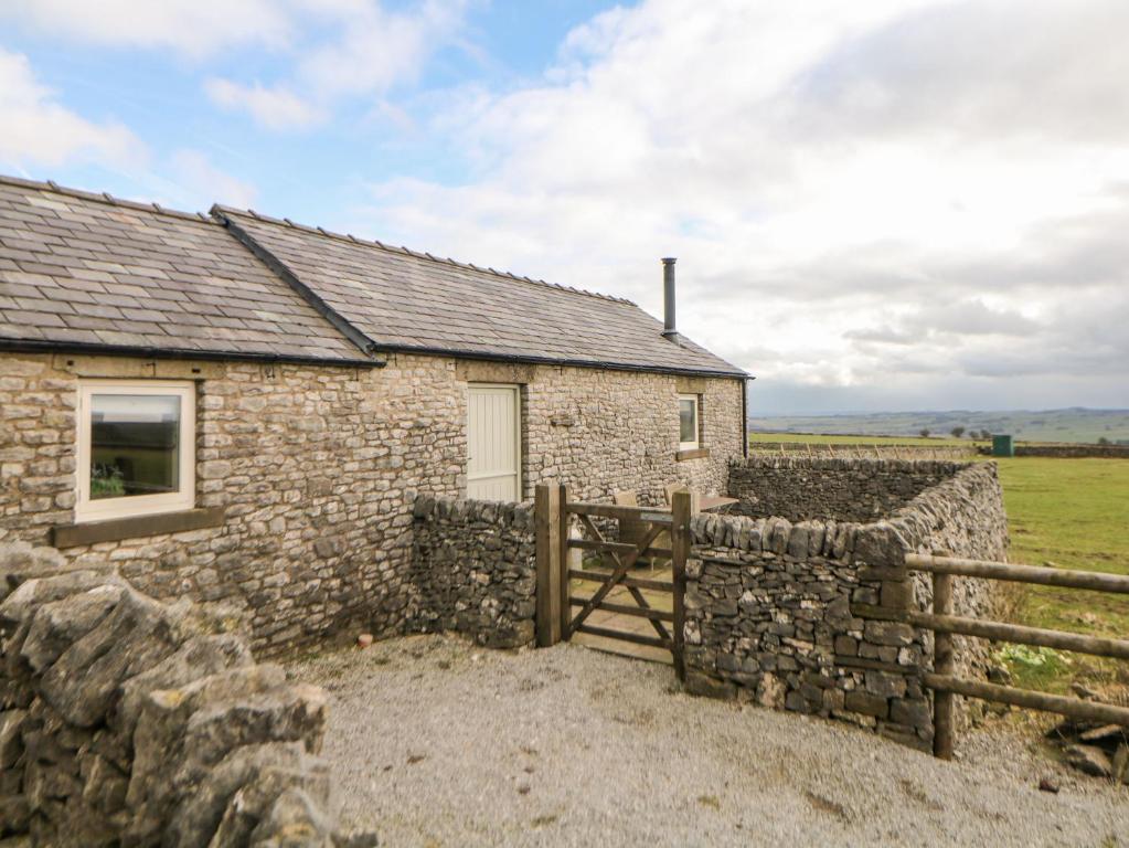 a stone house with a fence and a field at Five Wells Barn in Flagg