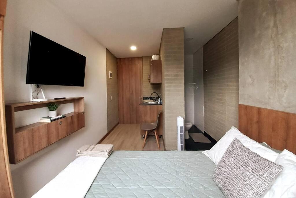 Schlafzimmer mit einem Bett und einem TV an der Wand in der Unterkunft 702 Belen, Loft amazing view in Medellín