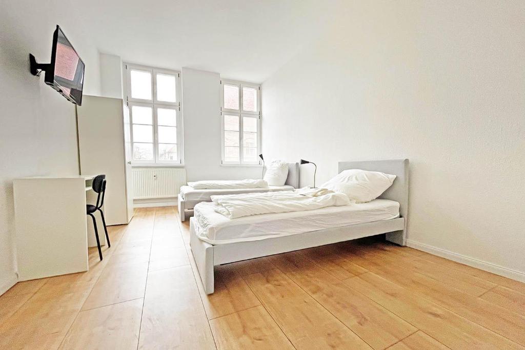 two beds in a white room with wooden floors at Chic Apartment in Jüterbog in Jüterbog