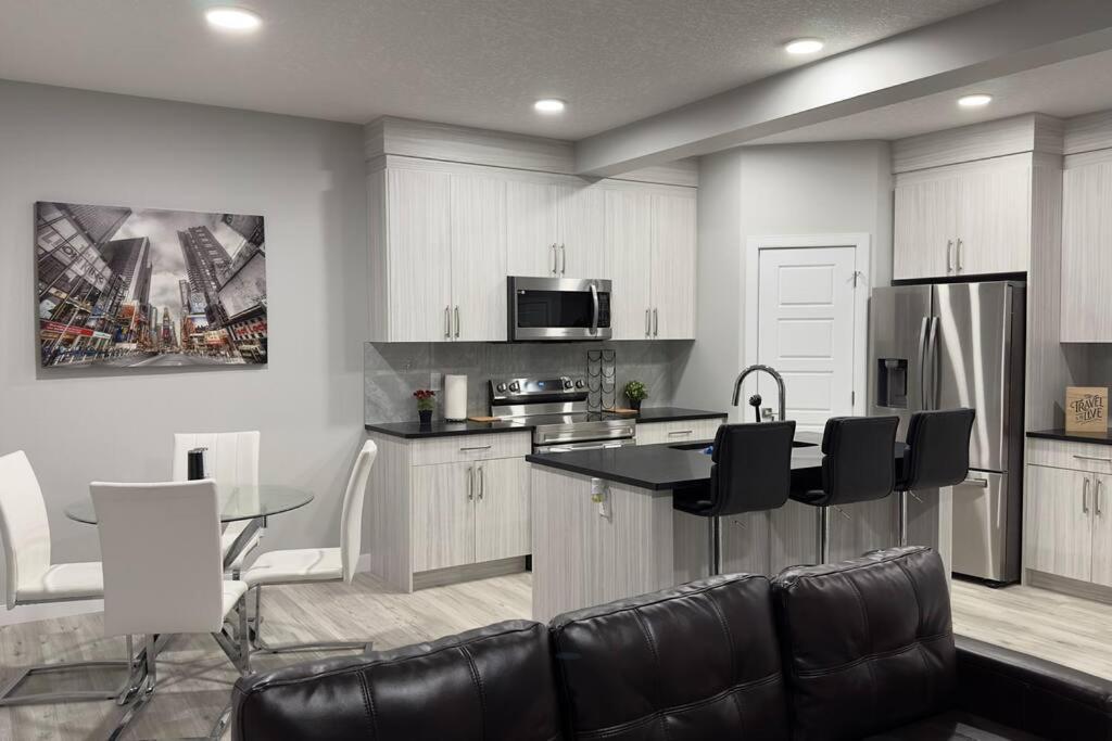 a kitchen with white cabinets and a table and chairs at 3 Bedroom Single Family Home in Edmonton