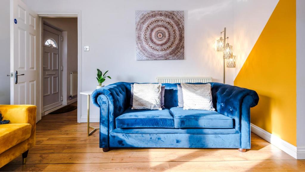 um sofá azul numa sala de estar com paredes amarelas em Newhall Road - 4 Bedroom Chester Home - Parking em Wervin