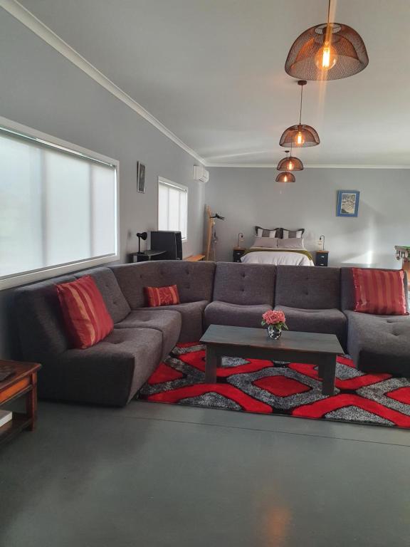 a living room with a gray couch and red pillows at The Red Shed in Matamata
