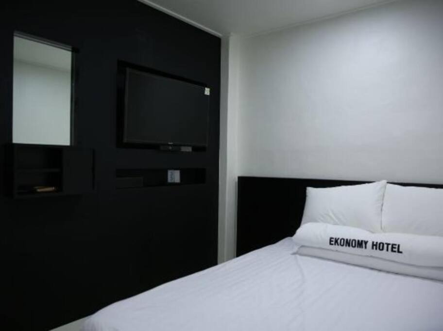 1 dormitorio con 1 cama blanca y TV. en Ekonomy Hotel, en Gumi