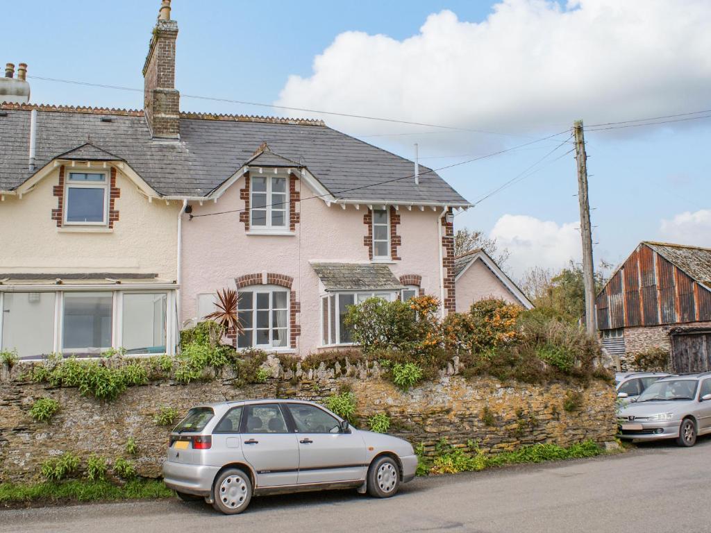 a white car parked in front of a pink house at The Old Post Office in Turnchapel