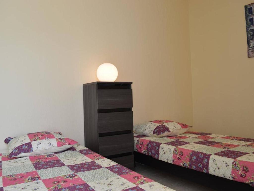 a bedroom with two beds and a dresser at Appartement Le Grau-du-Roi, 3 pièces, 6 personnes - FR-1-250-61 in Le Grau-du-Roi