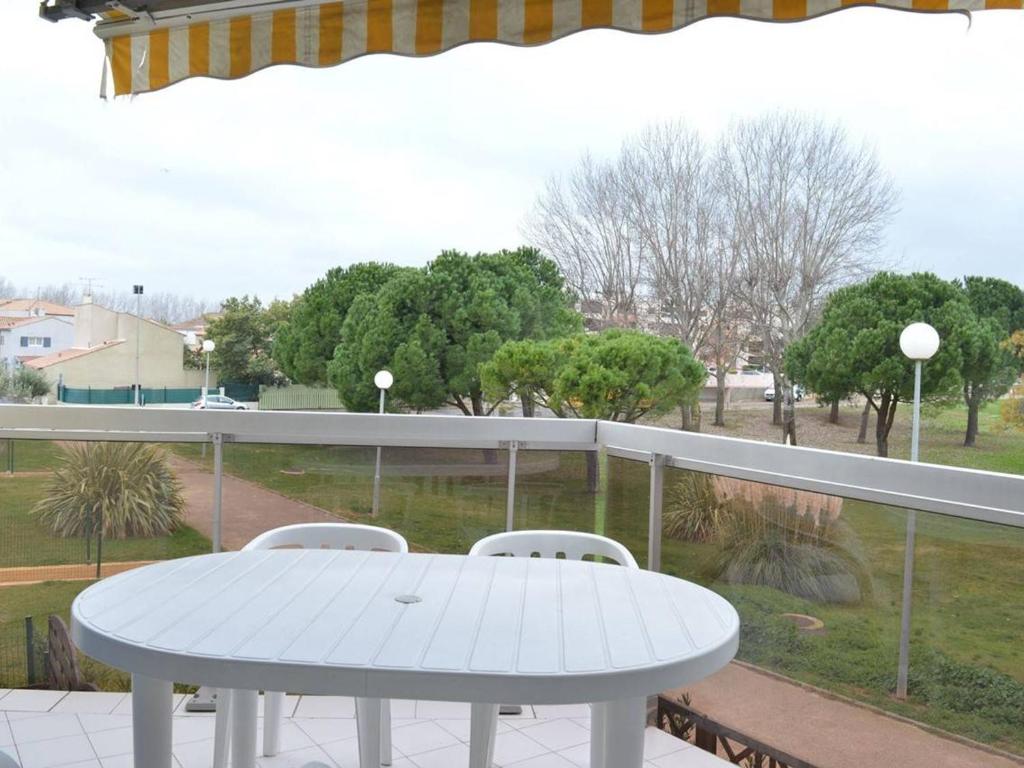 une table blanche et des chaises sur un balcon dans l'établissement Appartement cosy 6 pers avec parking, proche plage et commerces - Le Grau du Roi - FR-1-250-105, au Grau-du-Roi