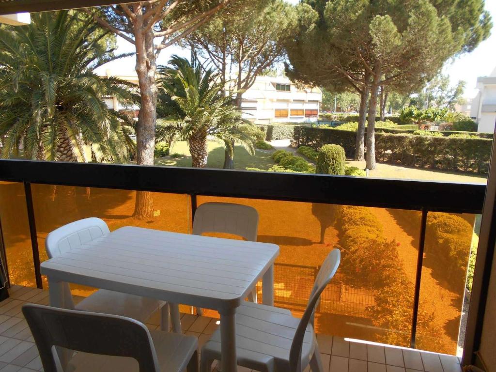 einen weißen Tisch und Stühle auf einem Balkon mit Bäumen in der Unterkunft Appartement Le Grau-du-Roi, 1 pièce, 4 personnes - FR-1-250-179 in Le Grau-du-Roi