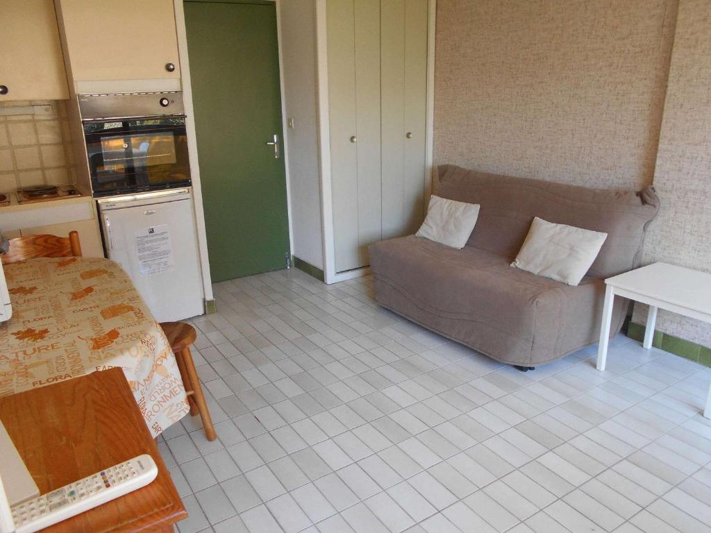 ein Wohnzimmer mit einem Sofa und einer Küche in der Unterkunft Appartement Le Grau-du-Roi, 1 pièce, 4 personnes - FR-1-250-179 in Le Grau-du-Roi